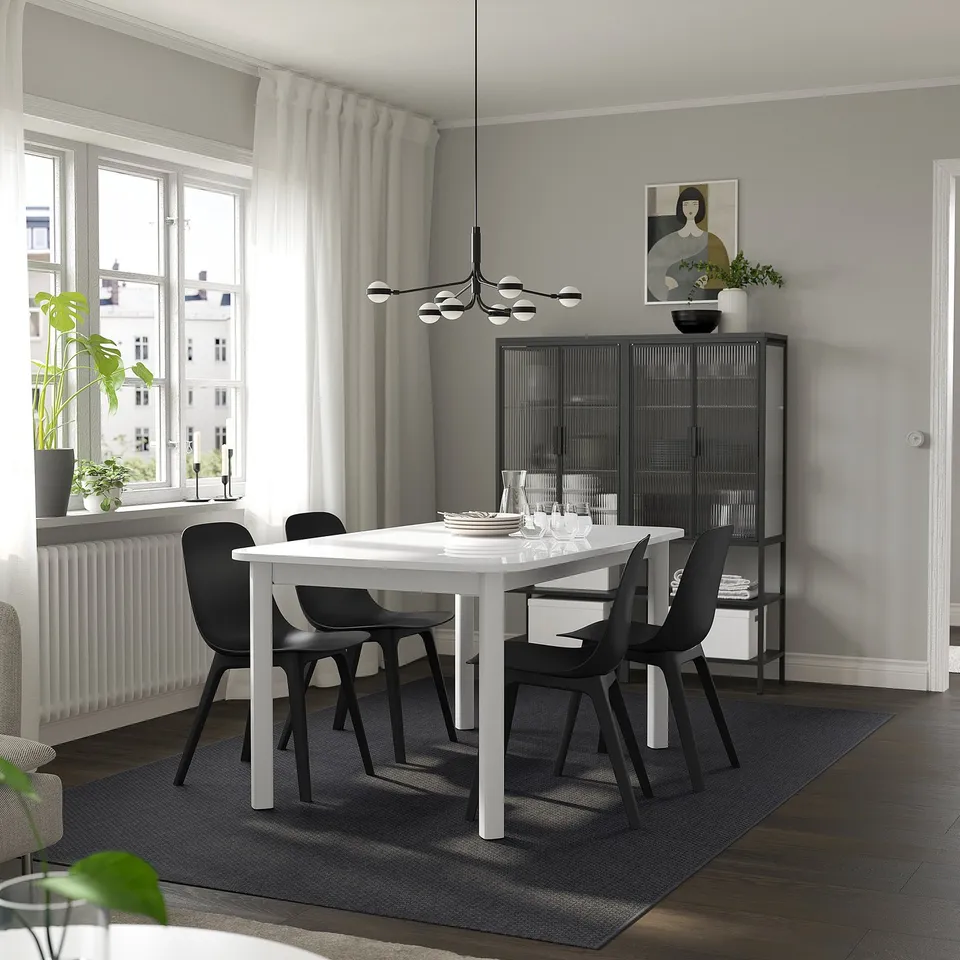 Dining room with STRANDTORP table, black chairs, cabinet, chandelier, urban view.