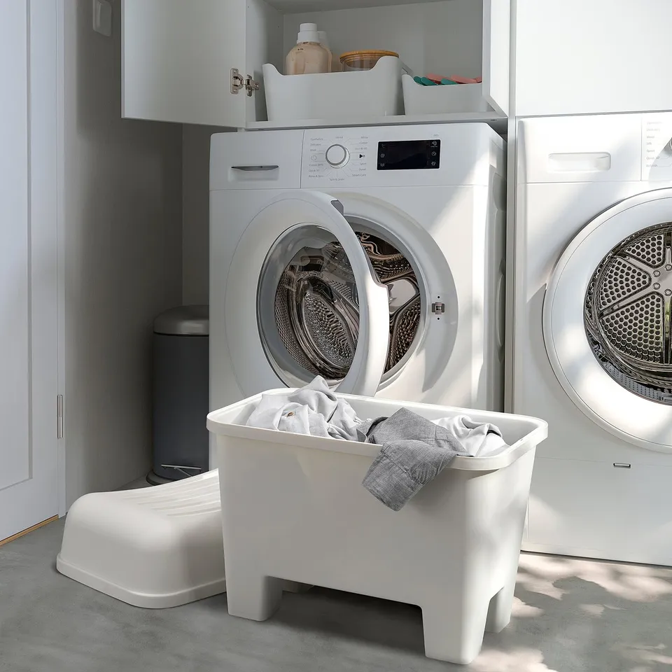White plastic stools & washing machines in laundry room. Central stool stores laundry.