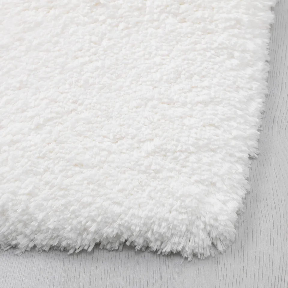 Soft, fluffy white bath mat with plush texture and non-slip backing.