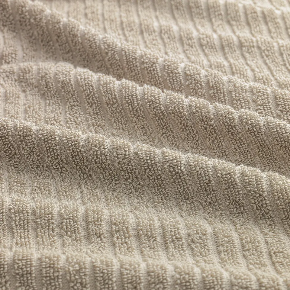 Close-up of soft, textured terry towel showcasing thick, absorbent stripes and smooth terry sections, highlighting its quality.
