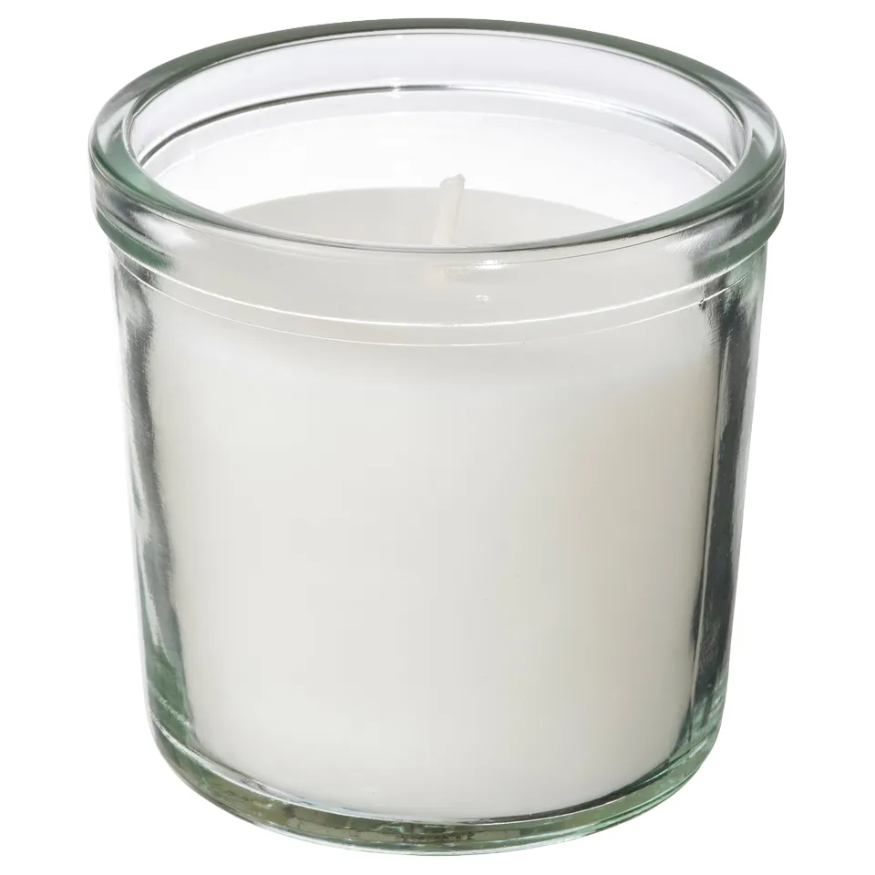 A TRÅDCYPRESS scented candle. Its white, in a clear glass jar, cylindrical with a simple design. The candle is mostly made of plant-based wax.