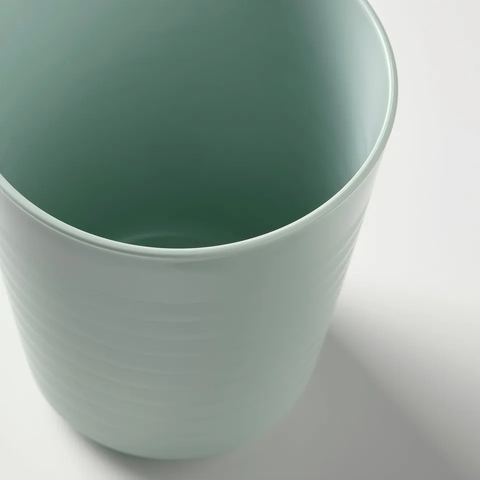 Round, light green plastic cup with a textured grip, designed for childrens use.