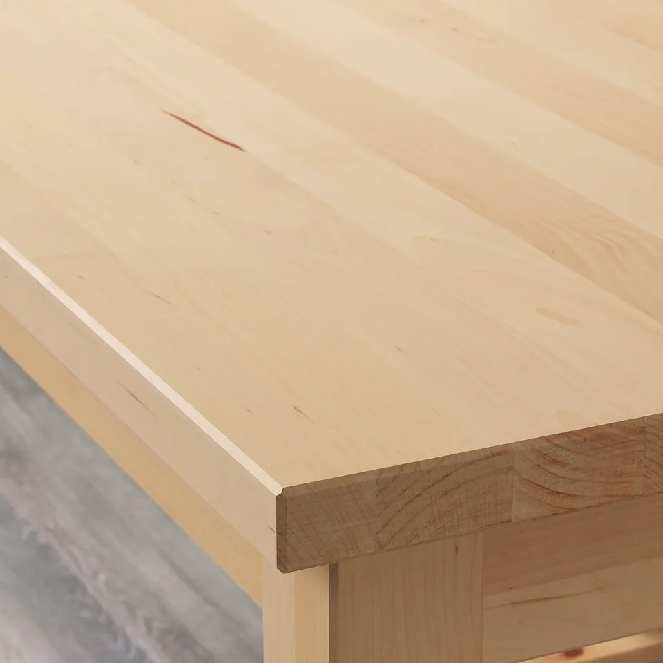 Close-up view of a smooth, well-crafted birch wood tabletop, showcasing its natural grain and light colour.