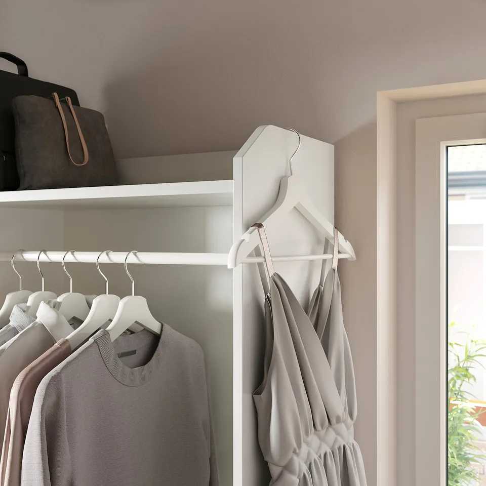 Closet with clothes hangers and shelf holding bags.