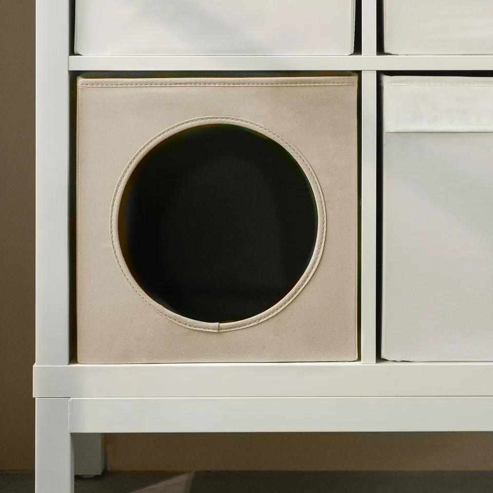 A folded fabric cat house designed for kallax shelving, featuring a circular entrance.