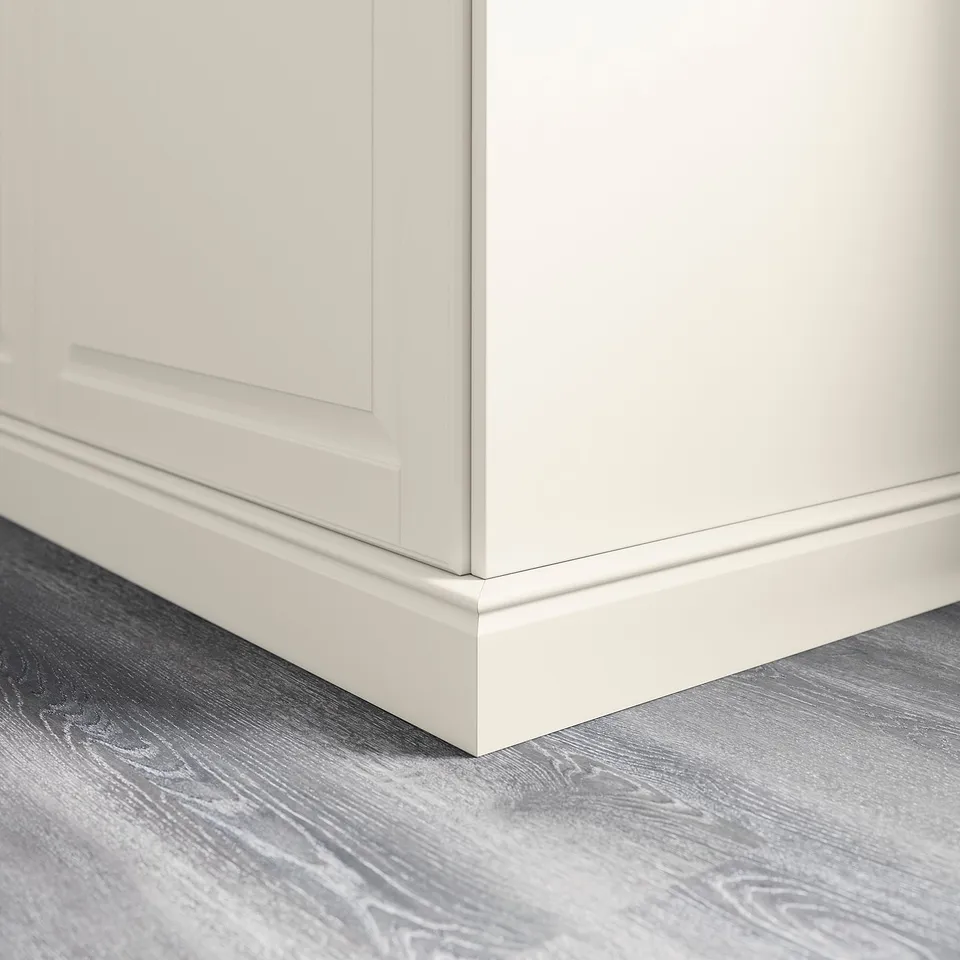 White kitchen cabinet plinth cover, neatly fitting between cabinet base and grey wooden floor.