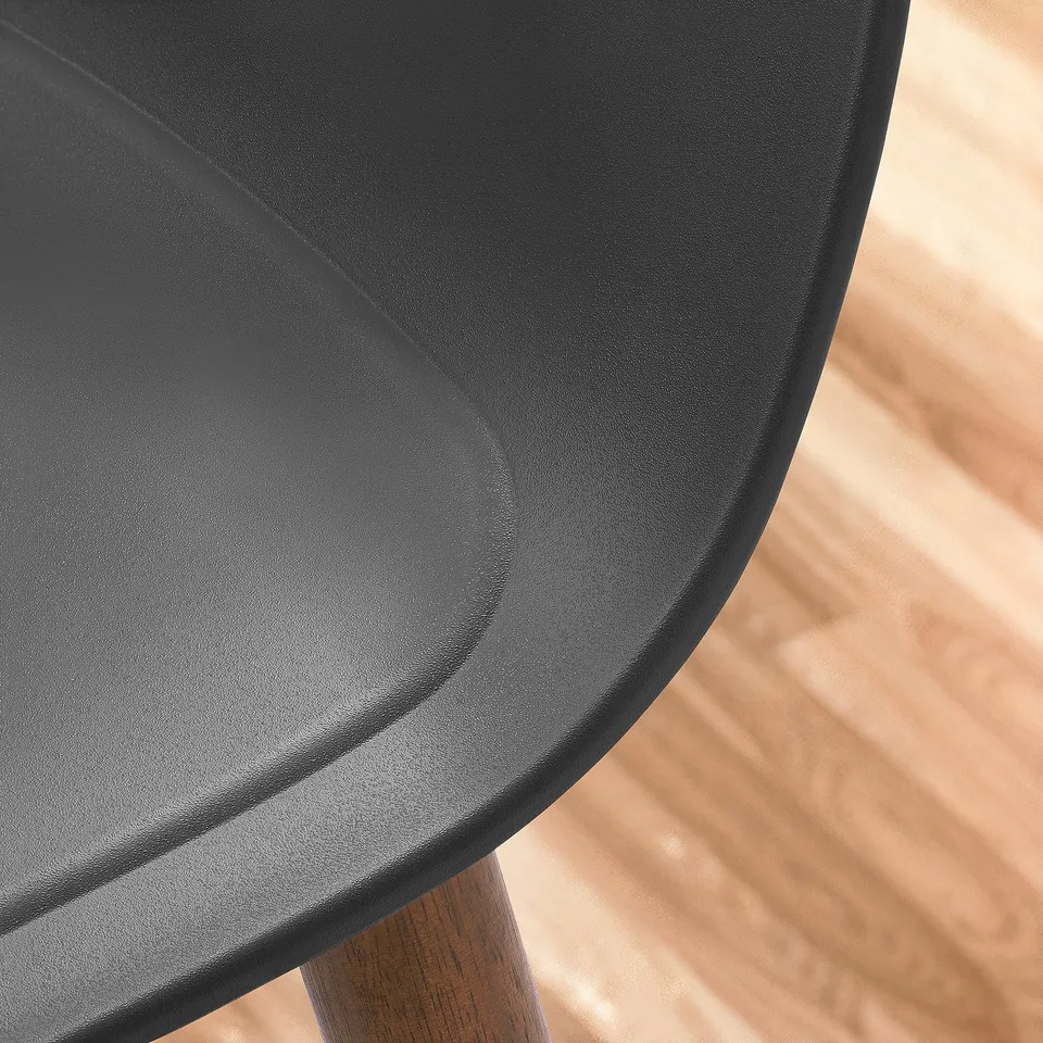 A modern chairs sleek, curved black seat with a smooth finish. The seats edges are slightly raised, providing a sense of support and comfort.