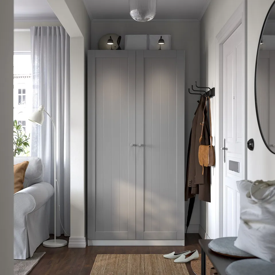 Minimalist entryway with PAX wardrobe, coat rack, lamp, armchair, and rug.