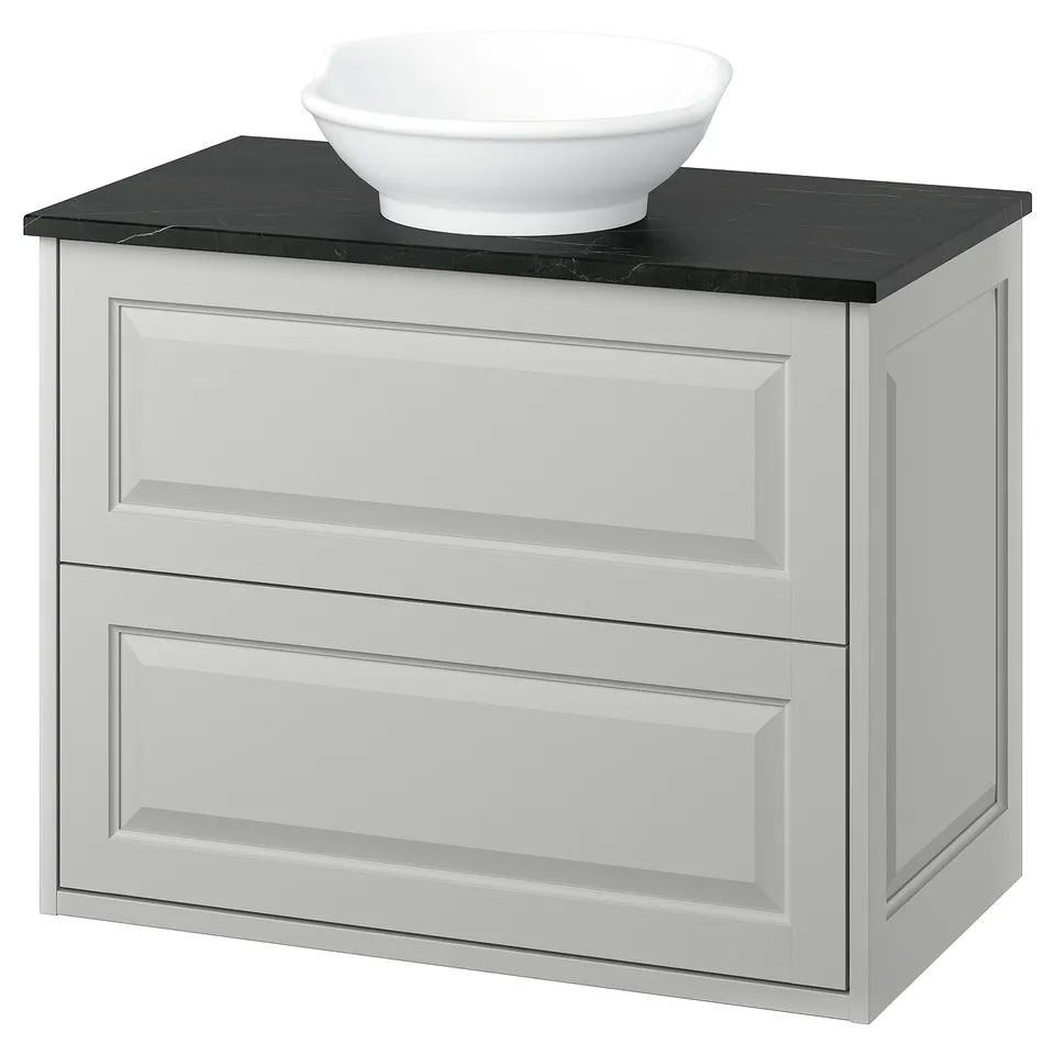 Modern white bathroom vanity with black countertop and bowl-shaped sink.