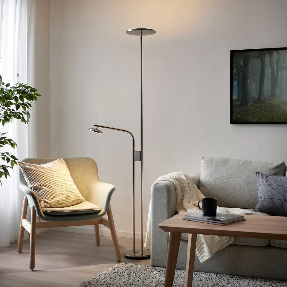 Living room with silver floor lamp, sofa, armchair, coffee table, and plant.