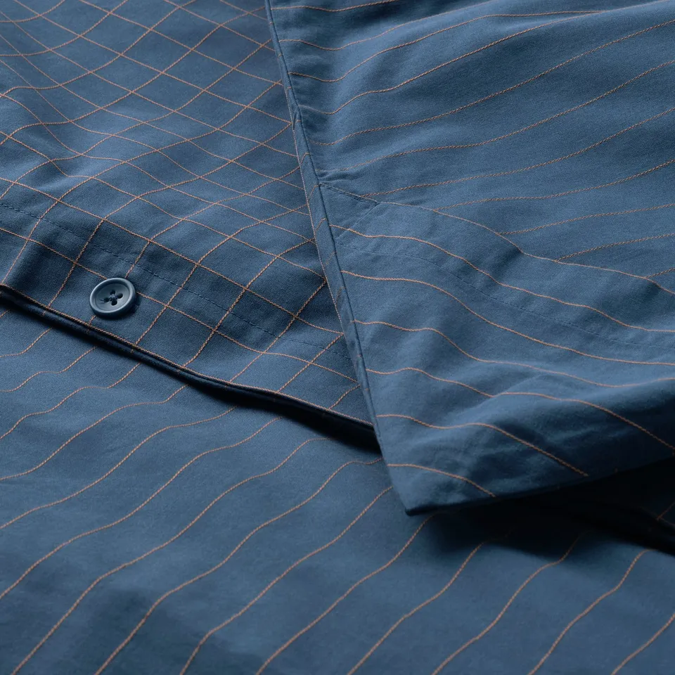 Close-up of DOFTAKLEJA duvet with chequered pattern, button, and stripes.