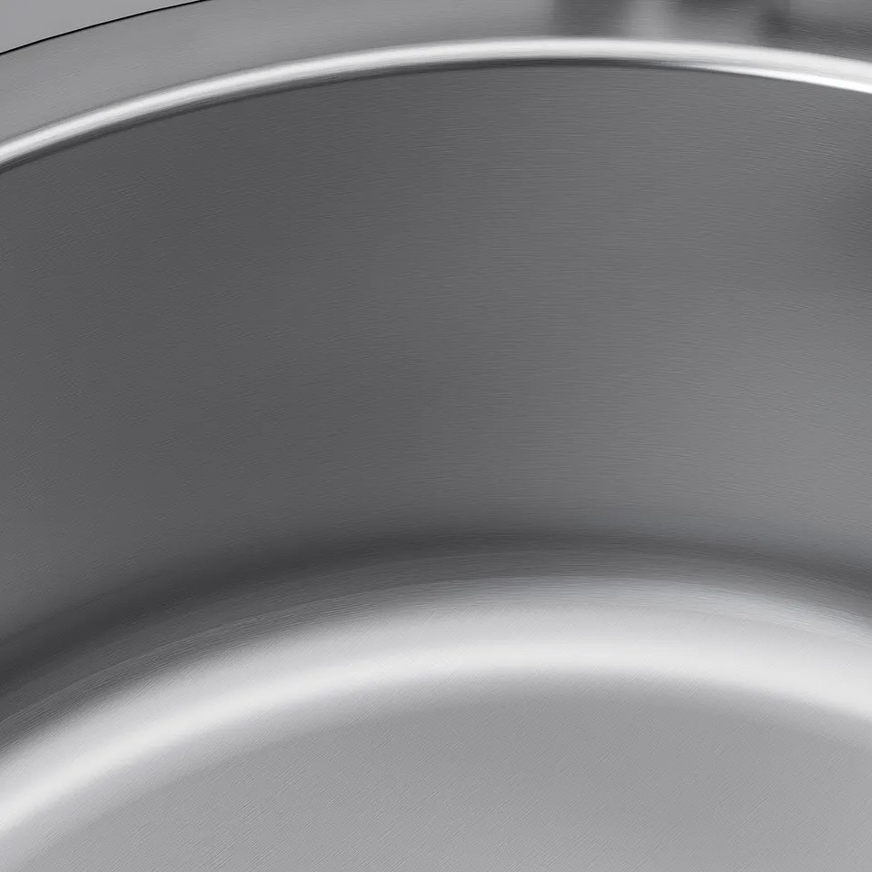 Close-up of shiny, seamless stainless steel sink, showcasing its smooth, reflective, and durable surface.
