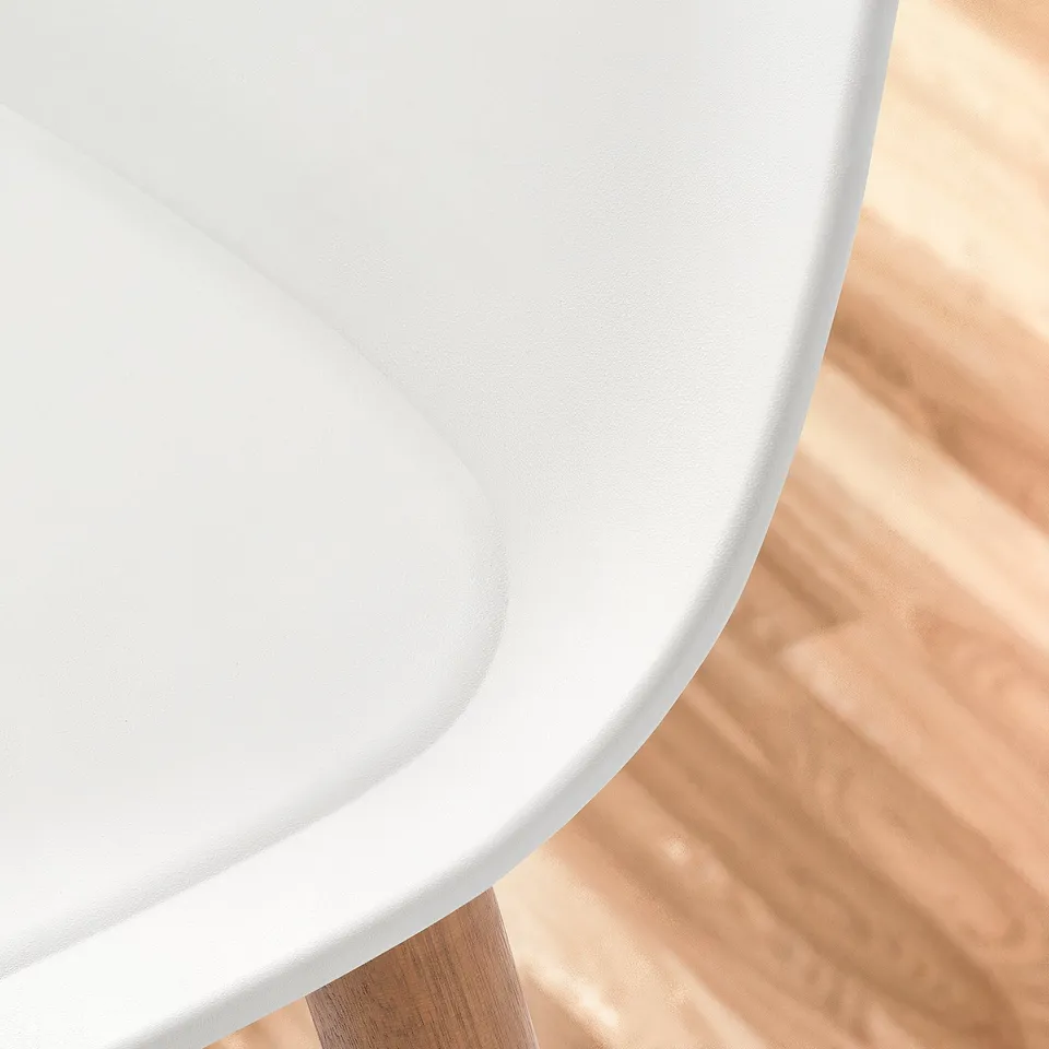 Close-up of sleek, modern chair edge. White curved seat, sturdy wood leg visible. Shows smooth, high-quality finish.