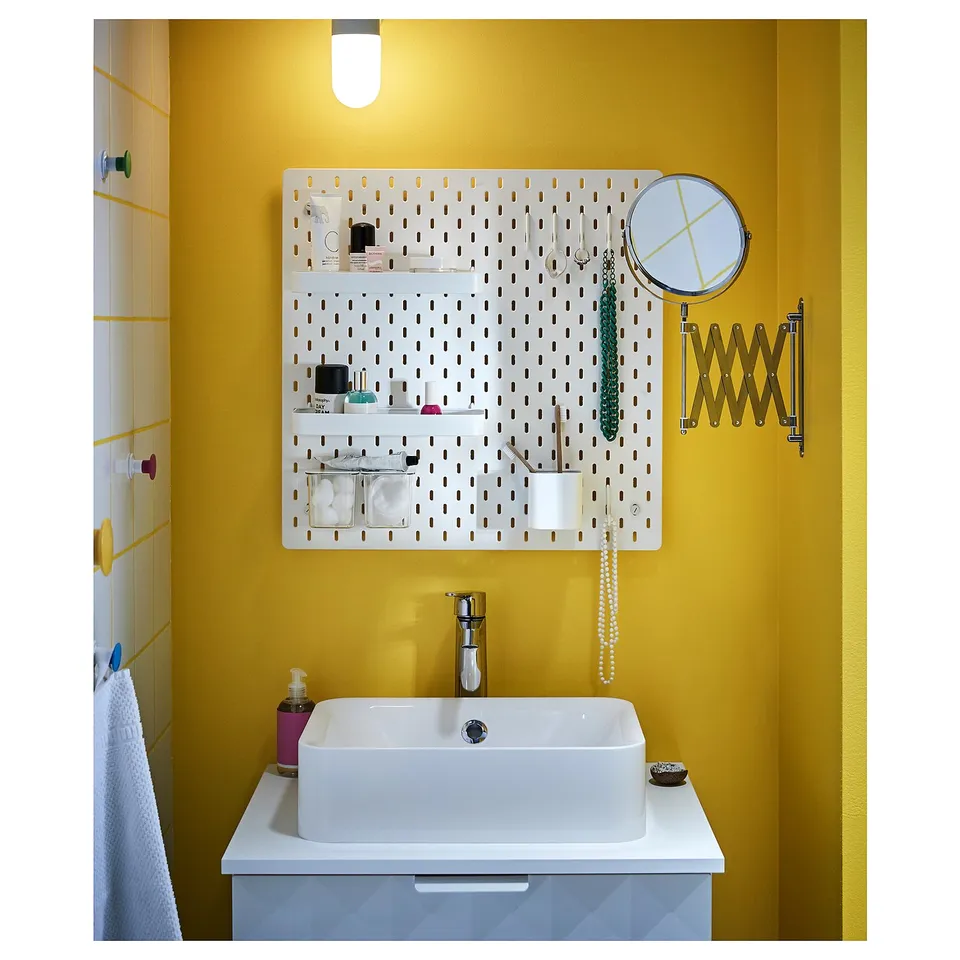 Bright yellow bathroom with white sink, pegboard, and magnifying mirror.