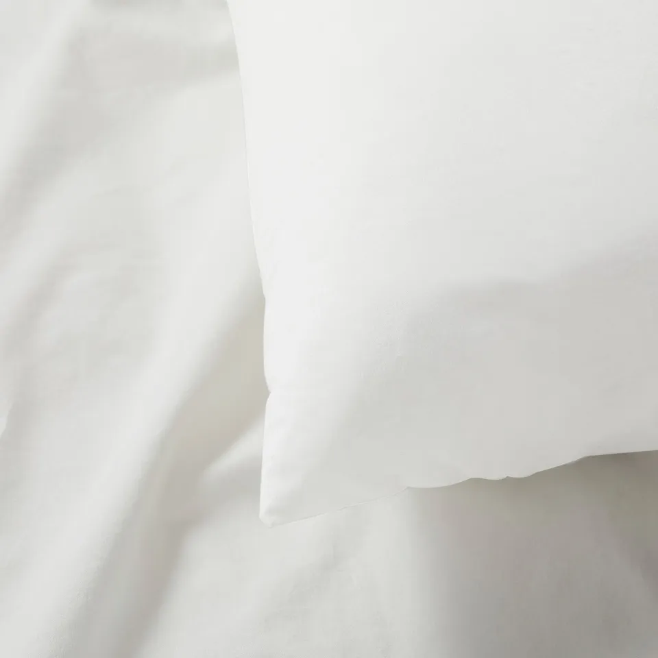 Close-up of crisp, white cotton pillowcase, smooth texture, natural weave, high-quality appearance.
