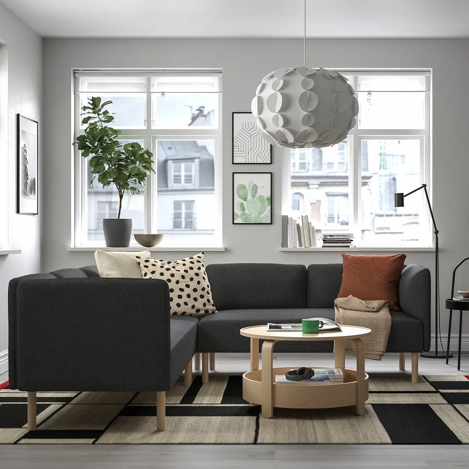 Modern living room with lillem grey modular sofa, abstract coffee table, patterned rug, and large window showcasing city views.