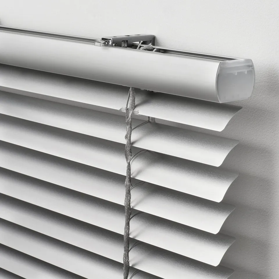 Close-up of modern white venetian blinds, showcasing sleek design and embedded cords for safe tilting, installed neatly against a plain wall.