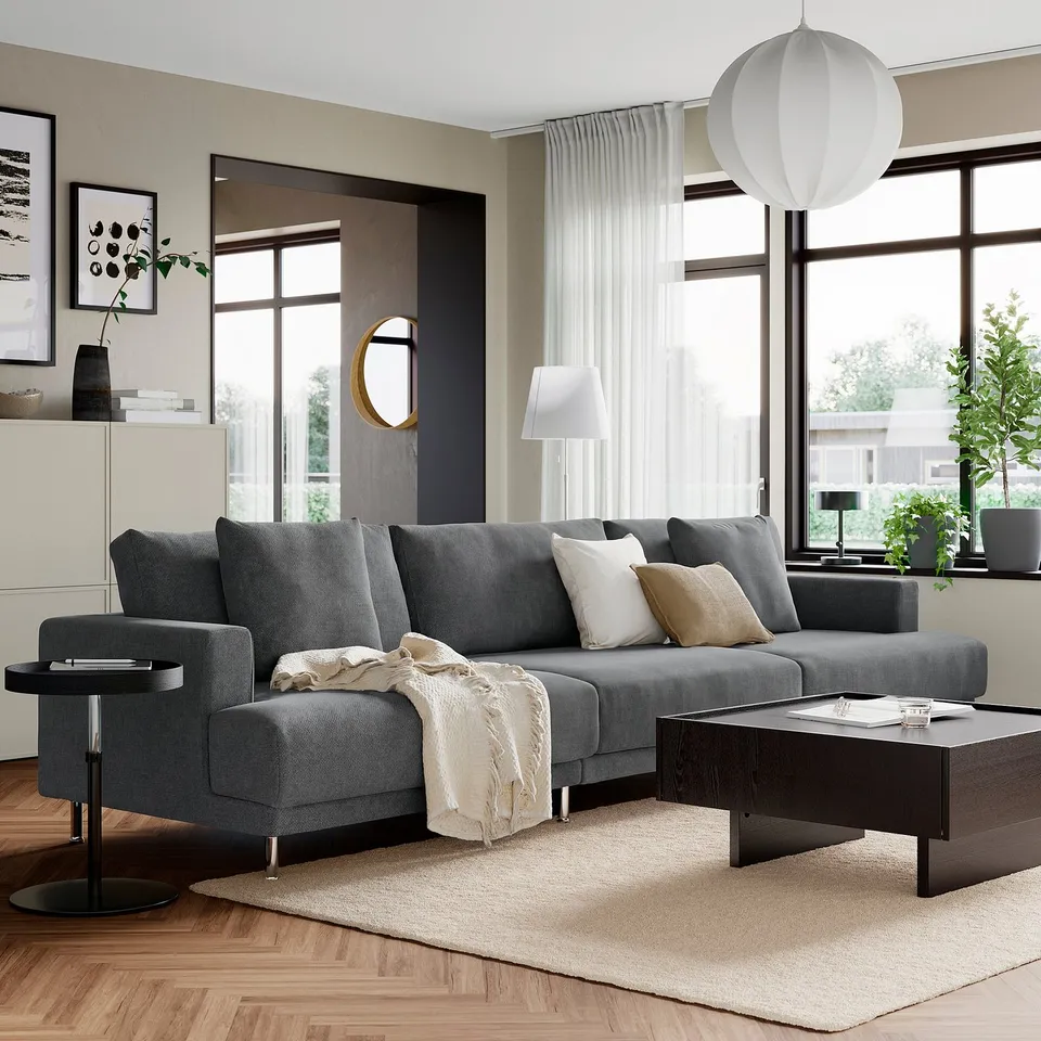Modern living room with grey sectional sofa, coffee table, and large windows. Neutral decor with pendant light.