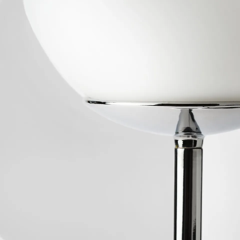 Modern chrome lamp with sleek glass shade, creating diffused elegant light.