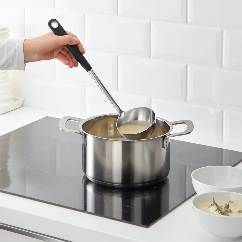 Cooking soup on glass stovetop with ladle.