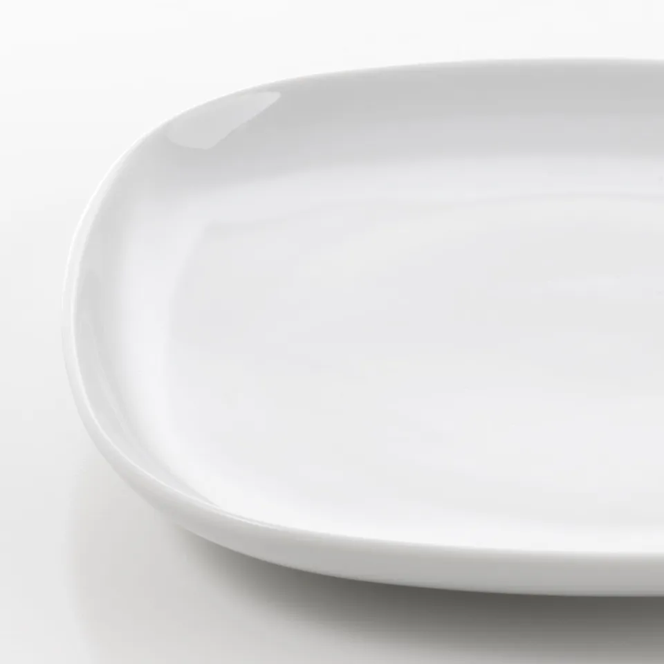 Close-up of a smooth, white porcelain plate with rounded edges. Highlights its sleek, durable surface and polished finish.
