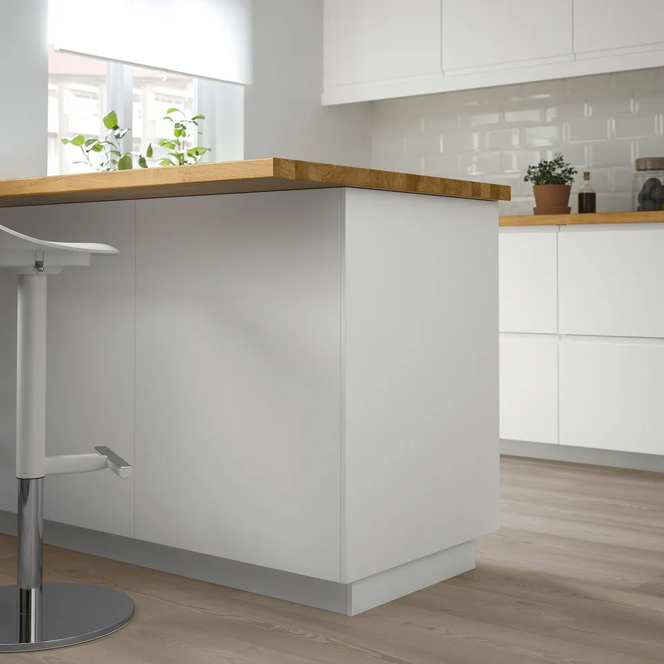 Modern kitchen island with white cabinets, light wood countertop, and adjustable stool. Sparse, clean design.