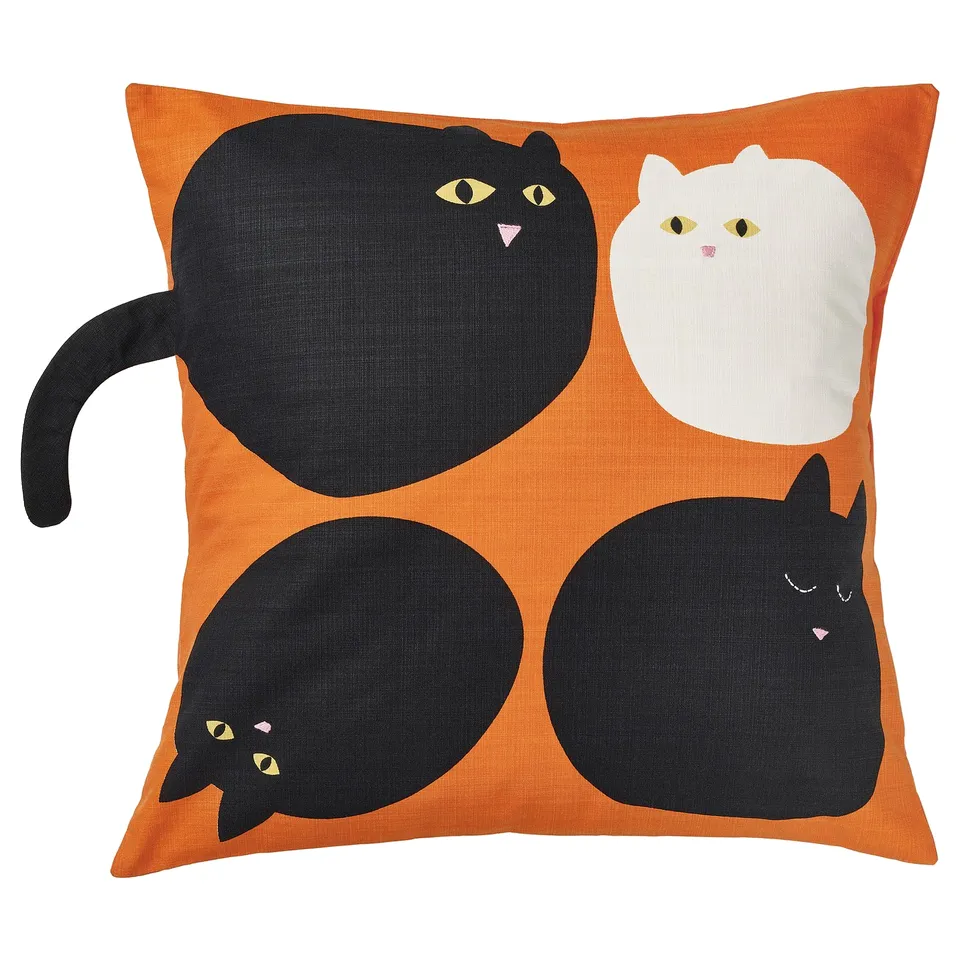 Orange square cushion with black cat head design, embroidered details, playful cat tail.