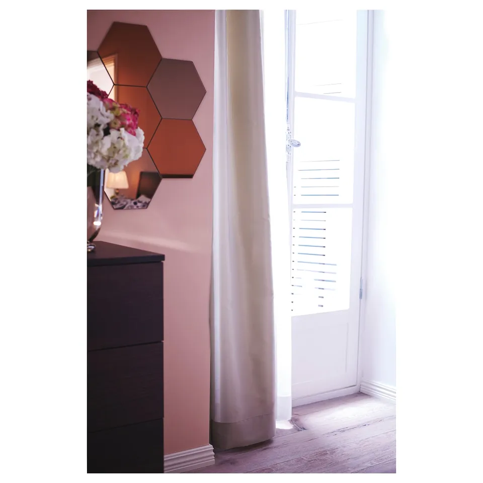 Room corner with large mirror on wall, dark wood dresser, light-colored floor, and closed window with shutters.