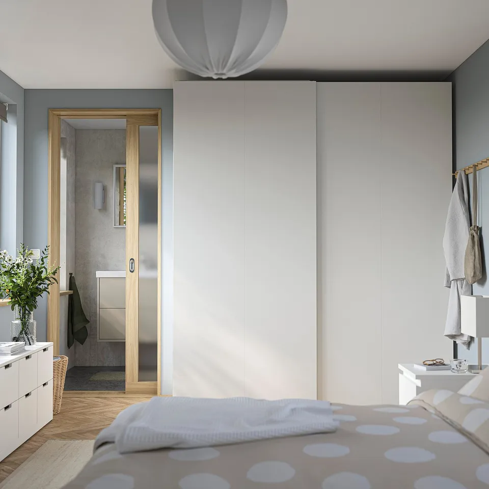 Modern bedroom with large PAX wardrobe, polka dot bed, and glass-door bathroom.