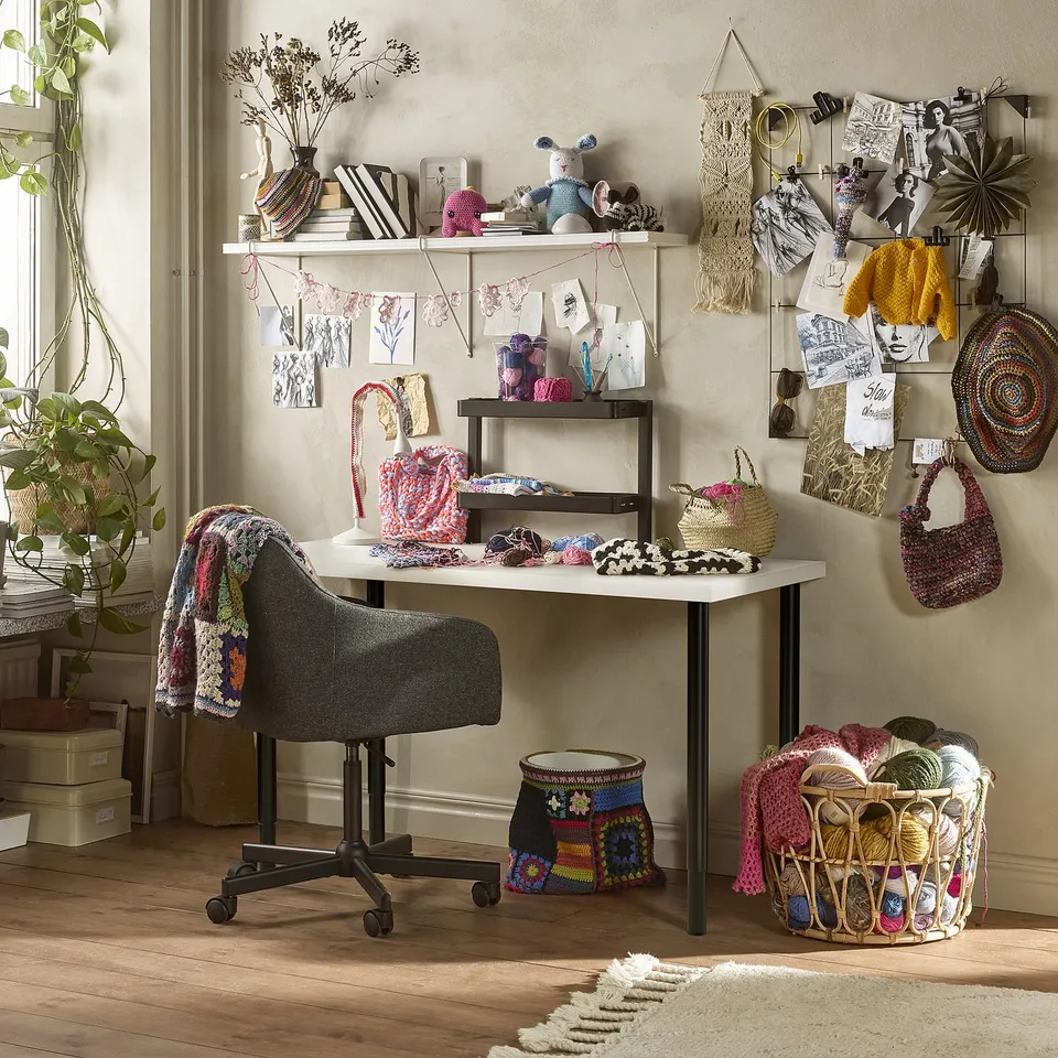 Craft room with LAGKAPTEN desk, grey chair, yarn, plants, and decorations. Desk smaller.