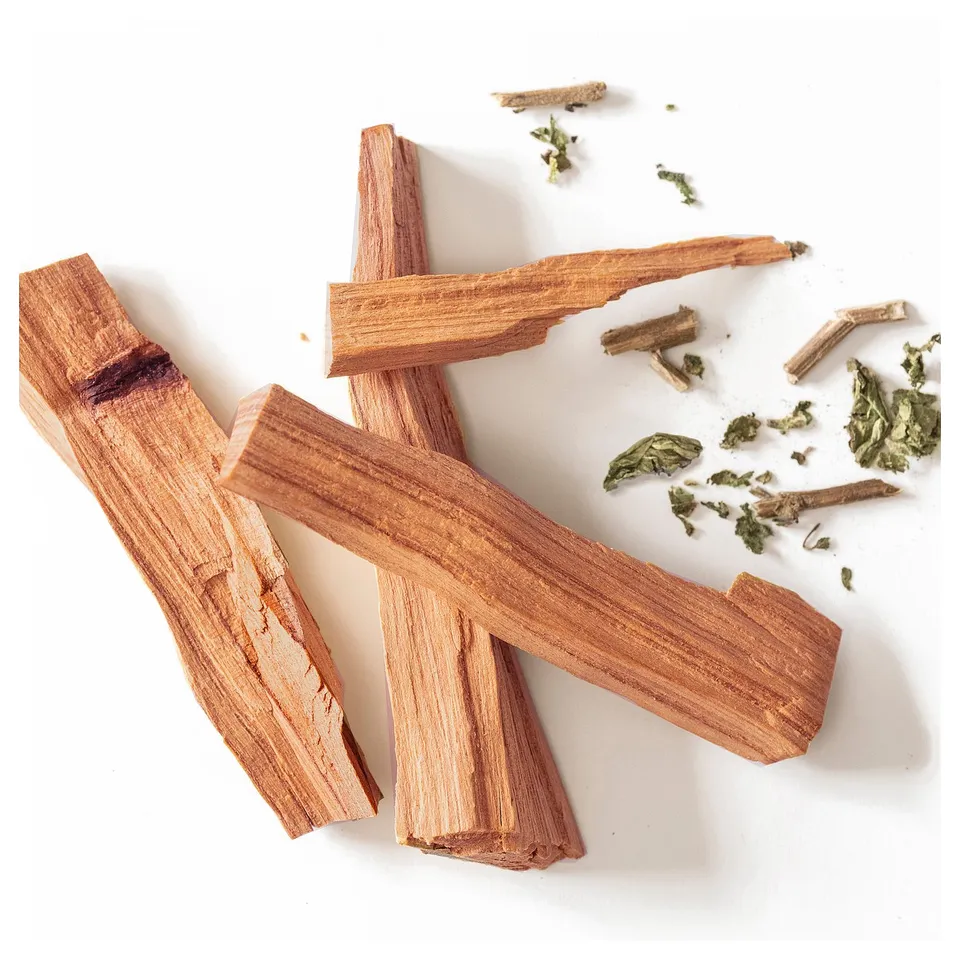 Four light brown wooden sticks, some with green leaves, on a white surface.
