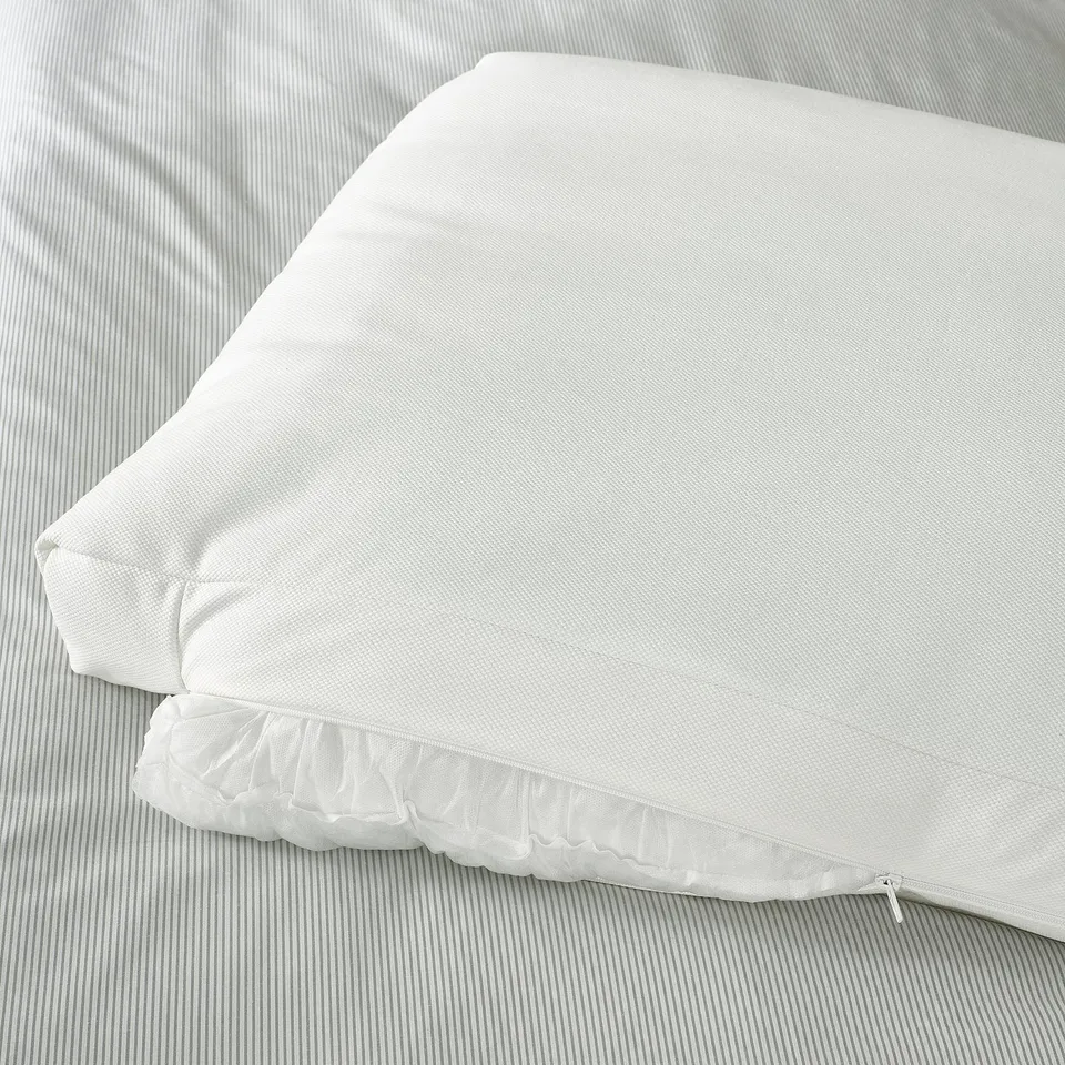 White bed frame with sloped headrest and pillows on striped bedding.