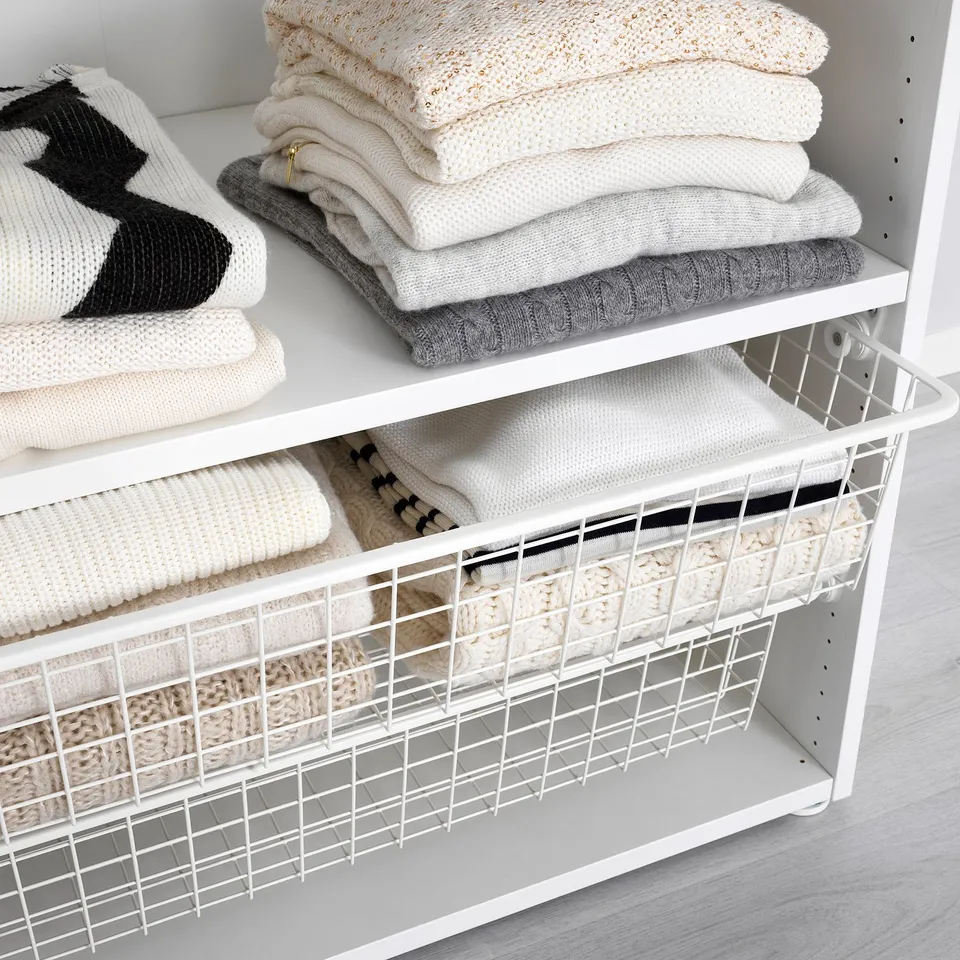 White shelf with wire baskets and folded clothes. Air circulates through mesh, keeping items fresh.