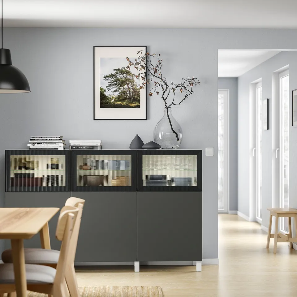 Elegant living room with black BESTÅ cabinet, wooden table, and nature art.