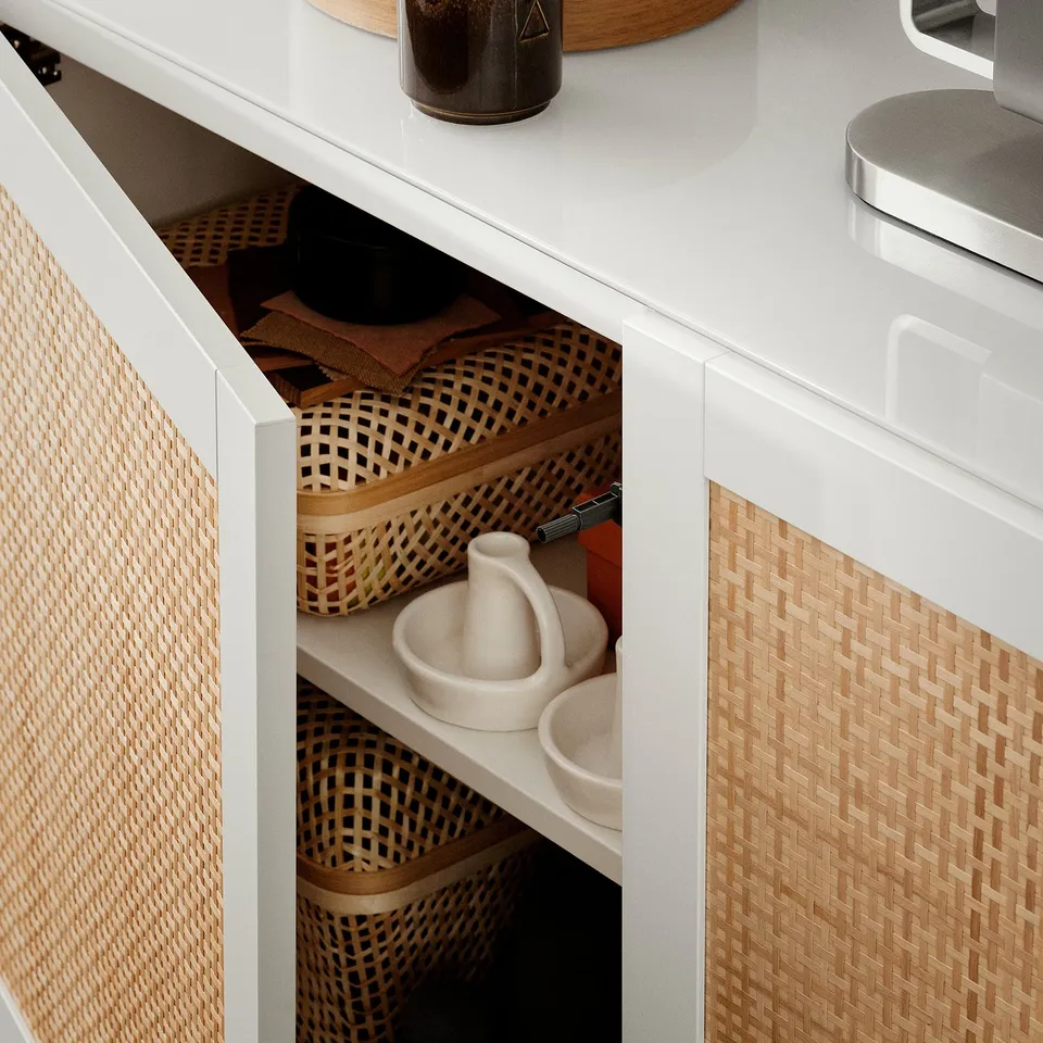 Open white cabinet with woven baskets, white ceramic, and a black pen.