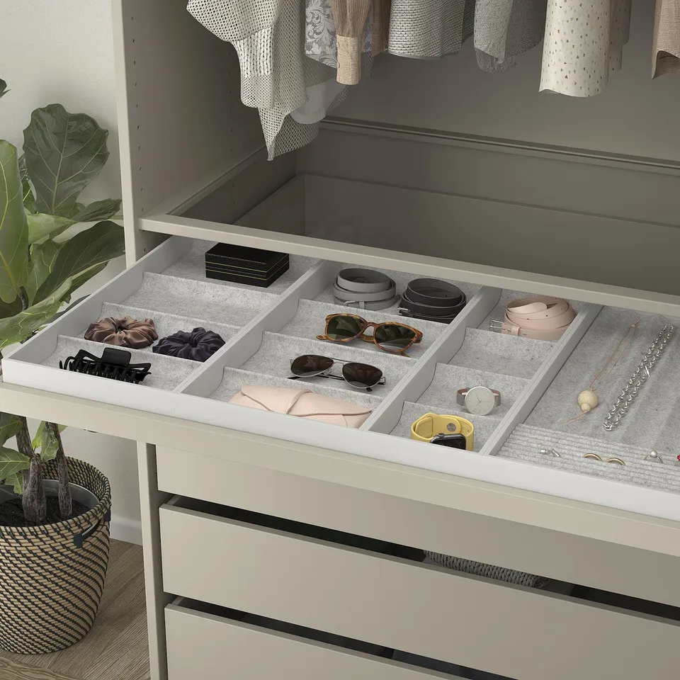 Open drawer organiser with felt-lined compartments for accessories, on top of wardrobe.