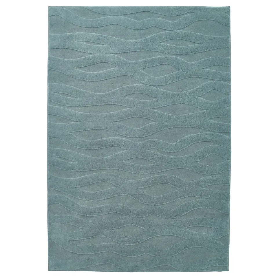 The VÄXELFEL rug is blue, rectangular, with soft, raised, wavy patterns, made from 100% recycled polyester.