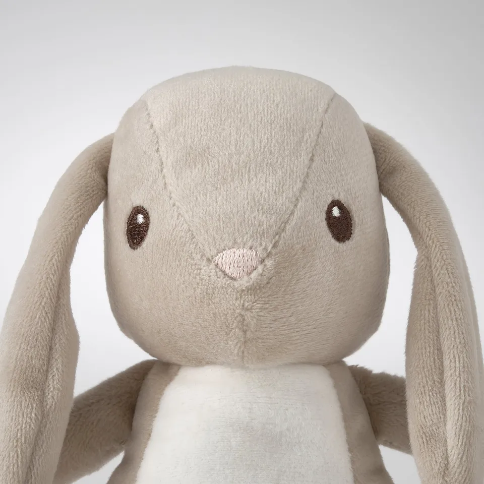 Soft, beige stuffed bunny toy with long ears, embroidered eyes and nose, looking cuddly and well-made.