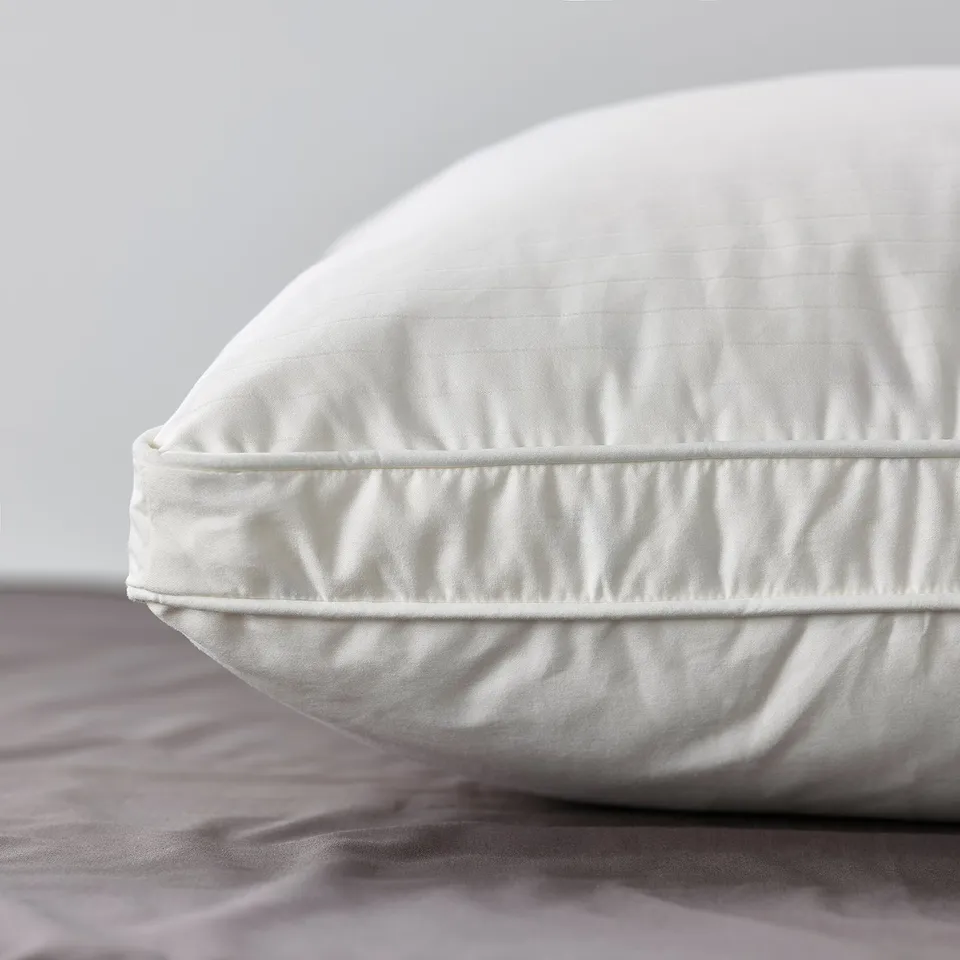 Close-up of a high-quality pillow with double piping, showcasing soft, luxurious fabric and fullness.