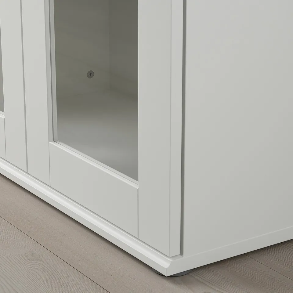 Close-up of a modern, white cabinet with clear, reflective glass door. High-quality finish, showcasing sleek design and sturdy build.