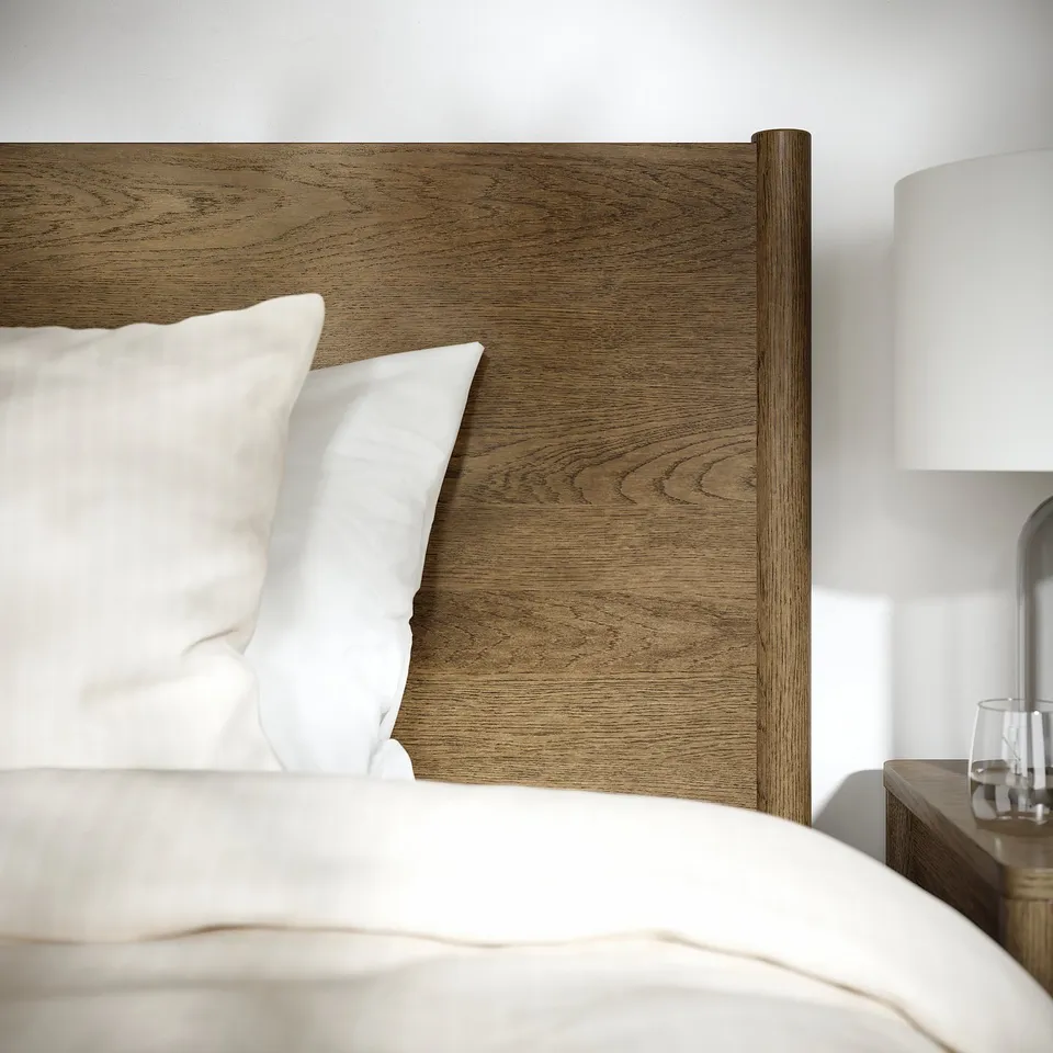 Bed with wooden headboard, plush white pillows, and bedside table, showcasing quality design and materials.