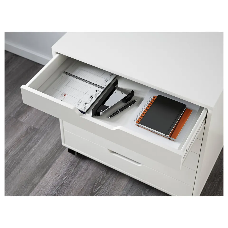 Open desk drawer with notebooks and office supplies, showing storage.