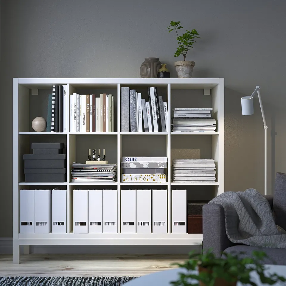 A white KALLAX storage unit with multiple shelves holding various items.