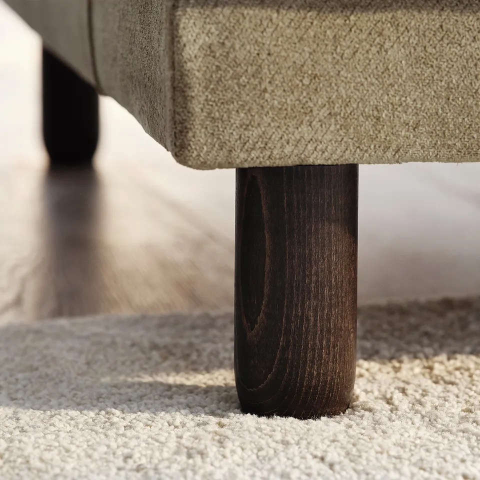 Close-up of UPPÅKRA sofa leg, showcasing sturdy wood finish and soft, textured fabric.