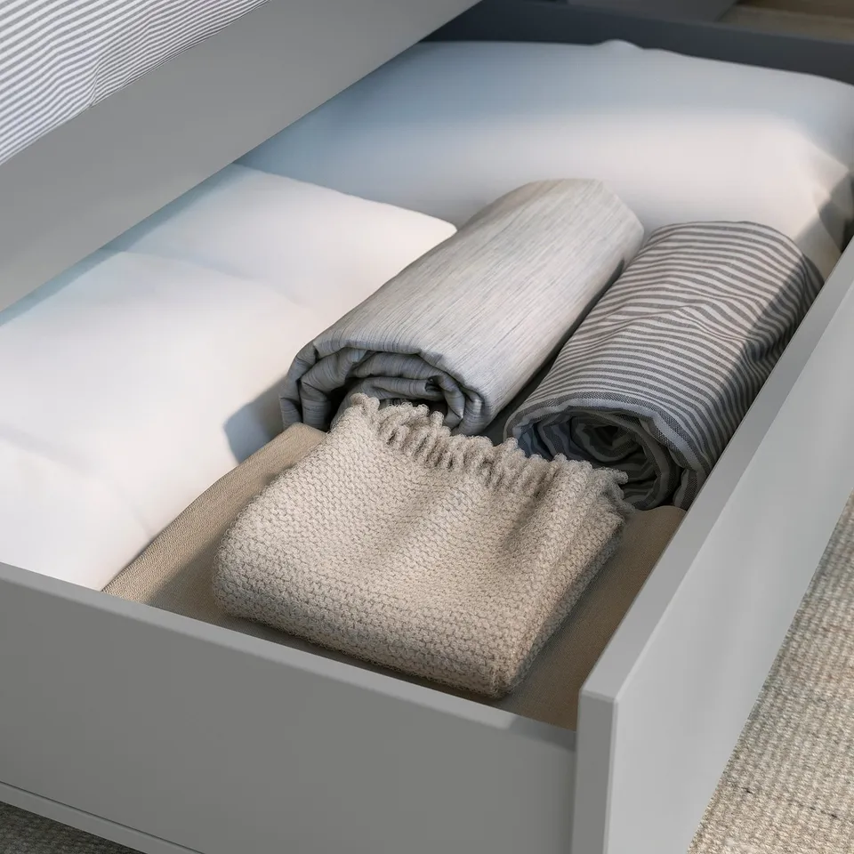 Bed drawer with folded blankets and sheets neatly organised.