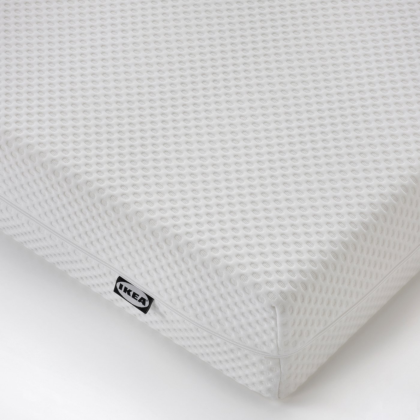 White foam mattress with textured cover, embroidered IKEA label, firm and high-quality.