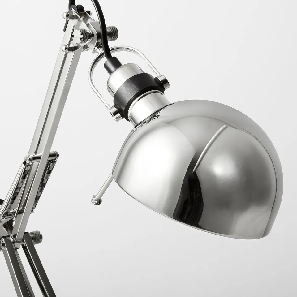 Silver desk lamp with adjustable arm and shade, designed for reading. High-quality metal finish, sleek and functional.