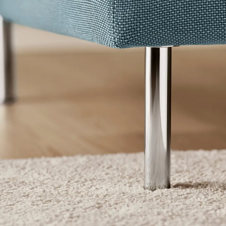 Close-up of a modern, sleek metal leg supporting a stylish, blue fabric chaise longue, showcasing quality design and materials.