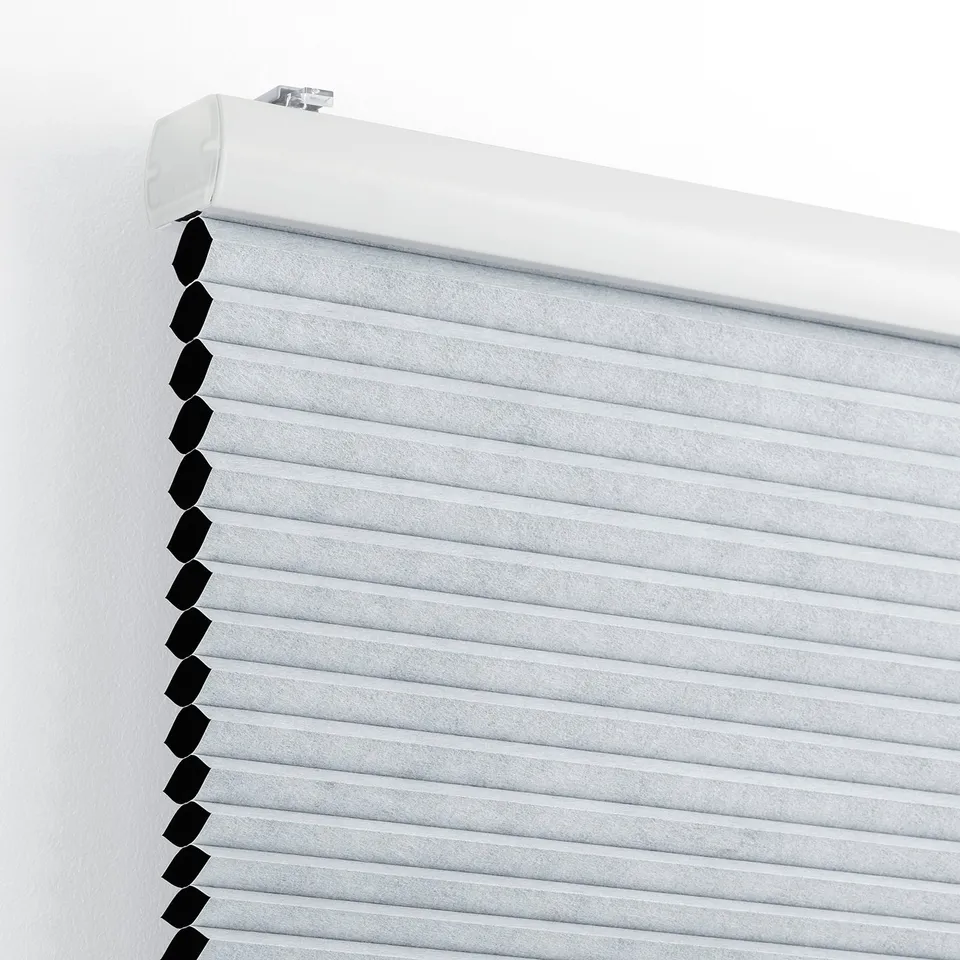 Close-up of white TRIPPEVALS block-out honeycomb blinds, showing light-blocking design and wall attachment.