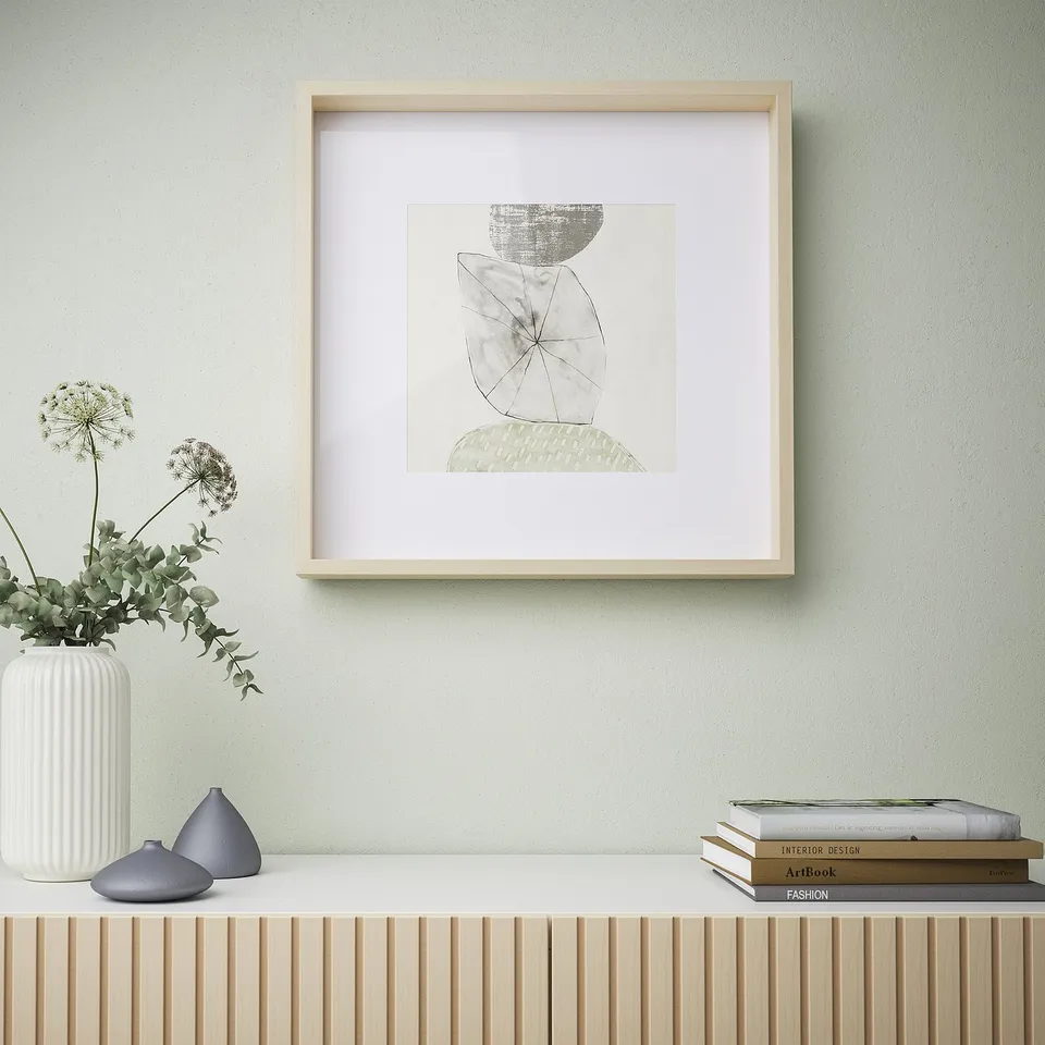 Framed minimalist art on light wall above wooden shelf with vases and books.